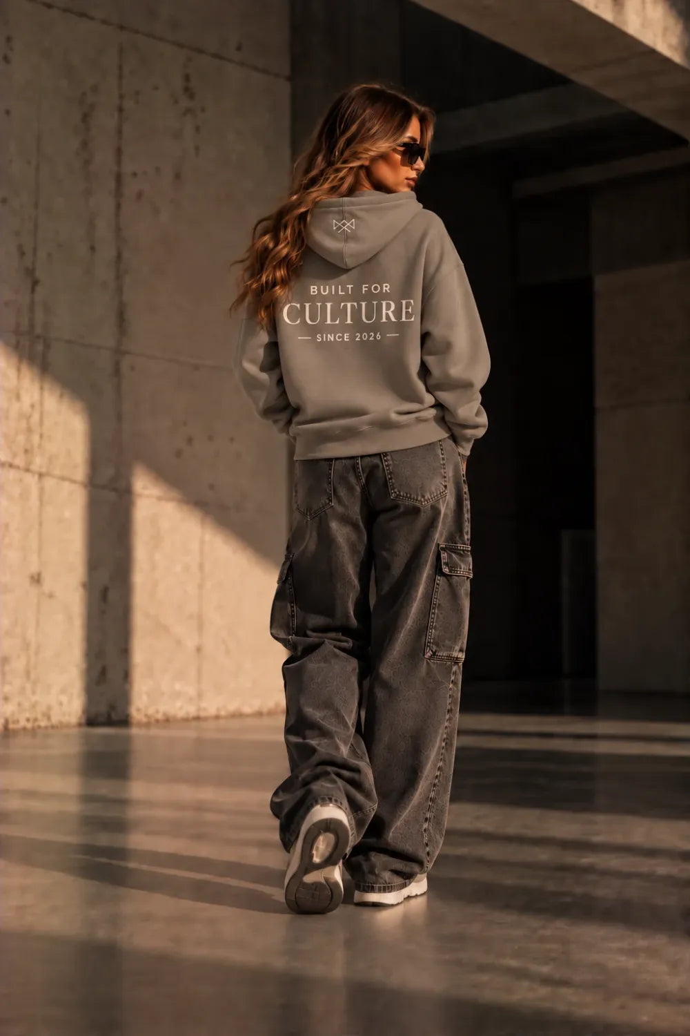 Model draagt Built For oversized hoodie beige met Built For Culture opdruk, achterkant